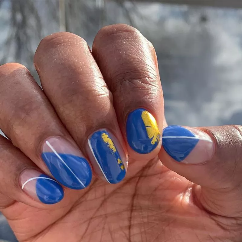Cobalt blue manicure with white stripe accents and gold foil detail