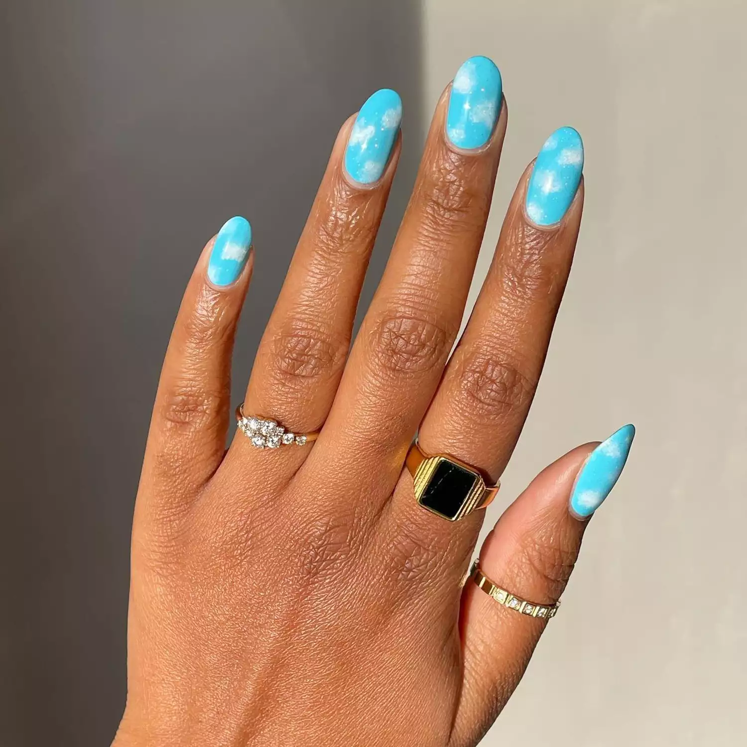 close up of woman's hand with bright blue cloud nail art