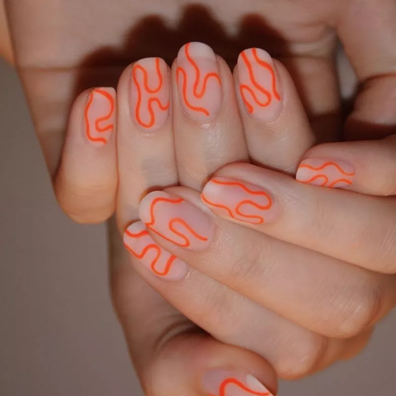 Blurred nude nails with matte neon orange squiggles