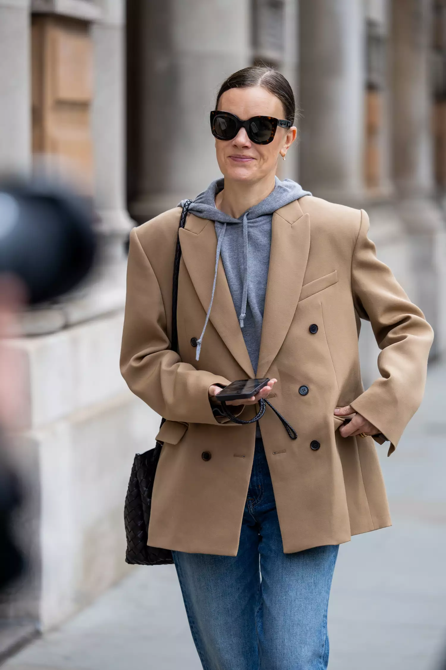 A guest wears beige blazer, grey hoody, denim jeans