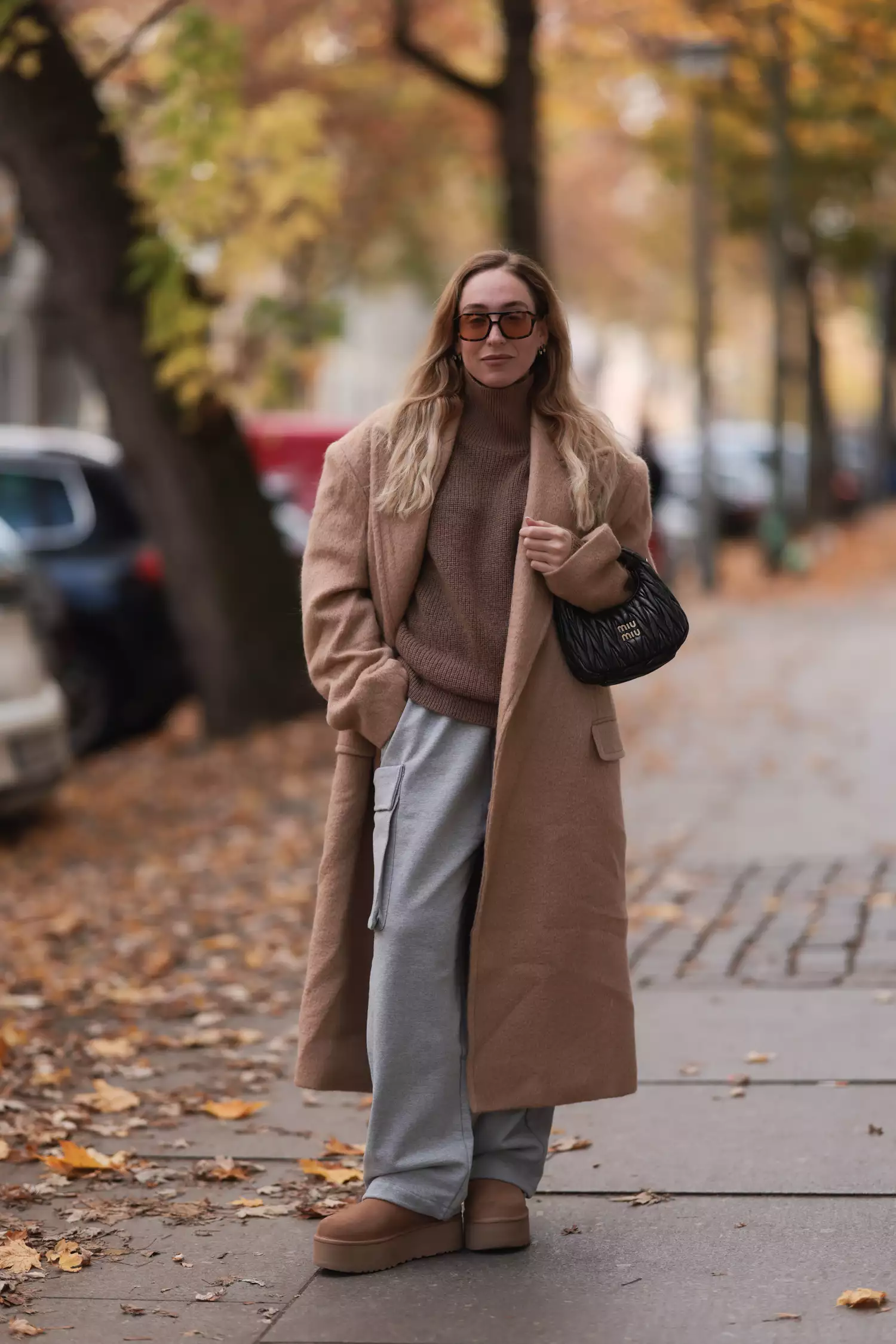 Sonia Lyson seen wearing a The Frankie Shop beige oversized coat and grey joggingpants pants, a Lala Berlin beige knit turtleneck sweater, Ugg plateau ultra mini beige boots, a Miu Miu Wander Hobo brown leather bag