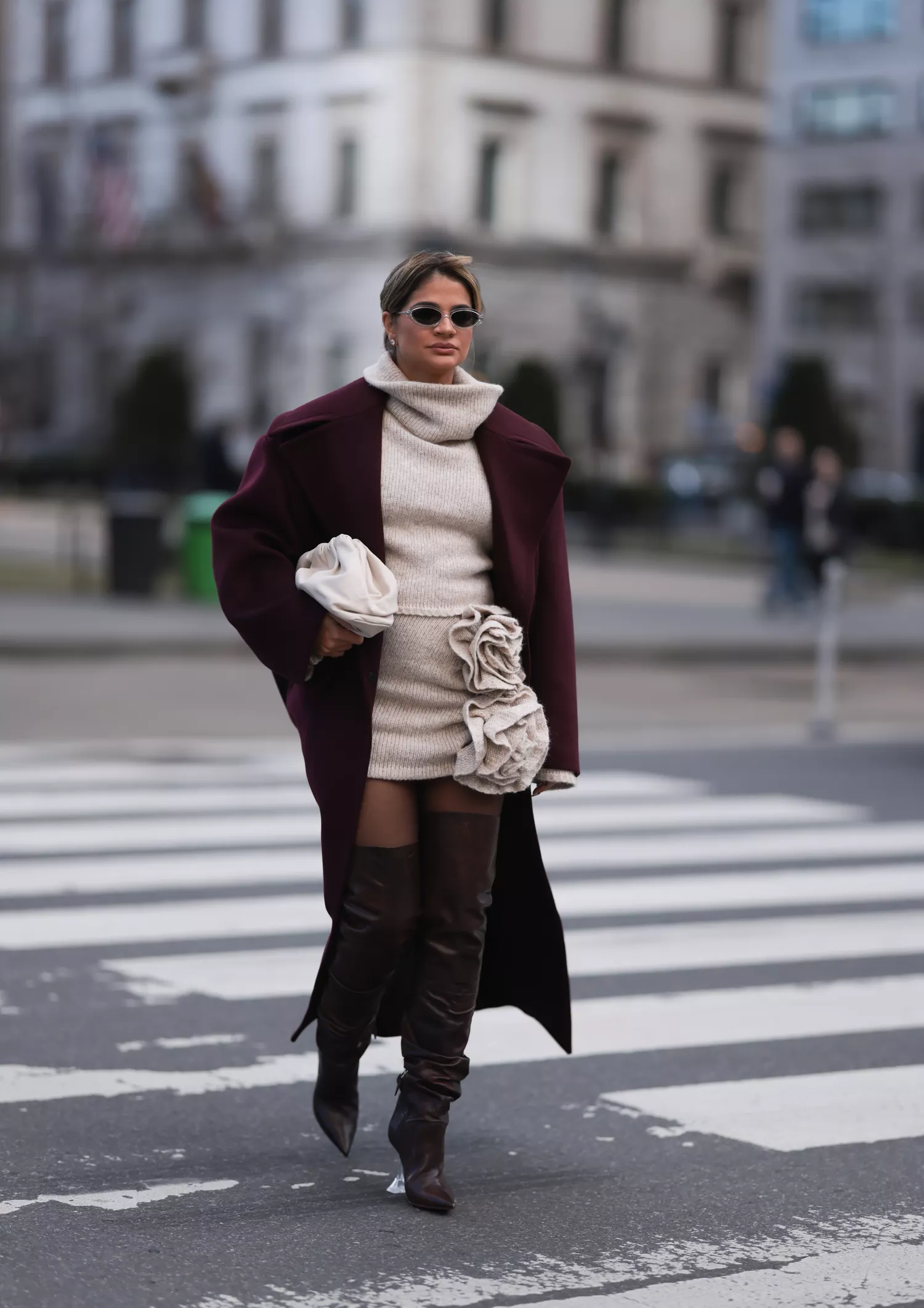 Thassia Naves seen wearing a white bag by Bottega Veneta, a long dark red coat, a beige knit dress and dark shades